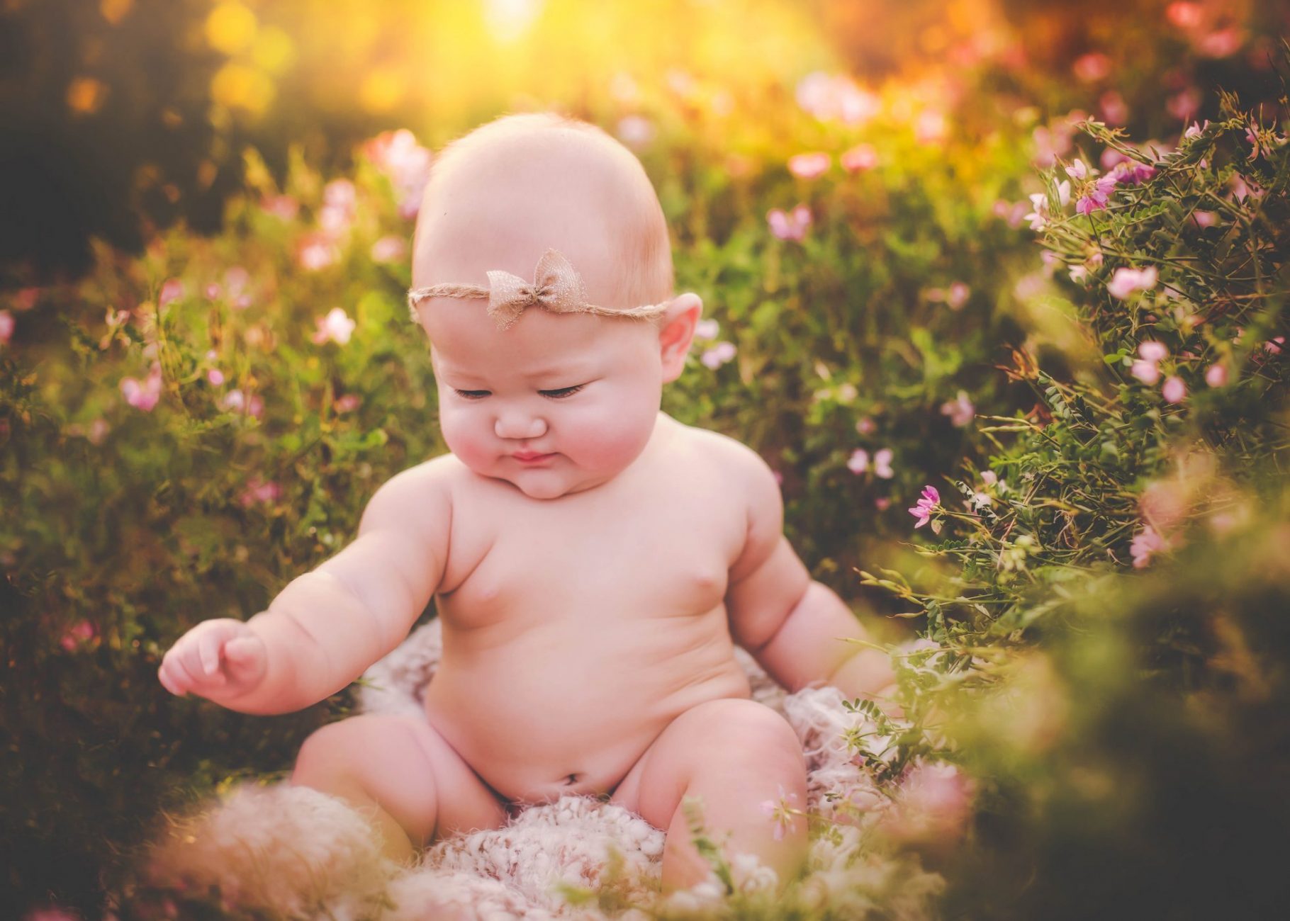 a baby sitting in the grass with flowers