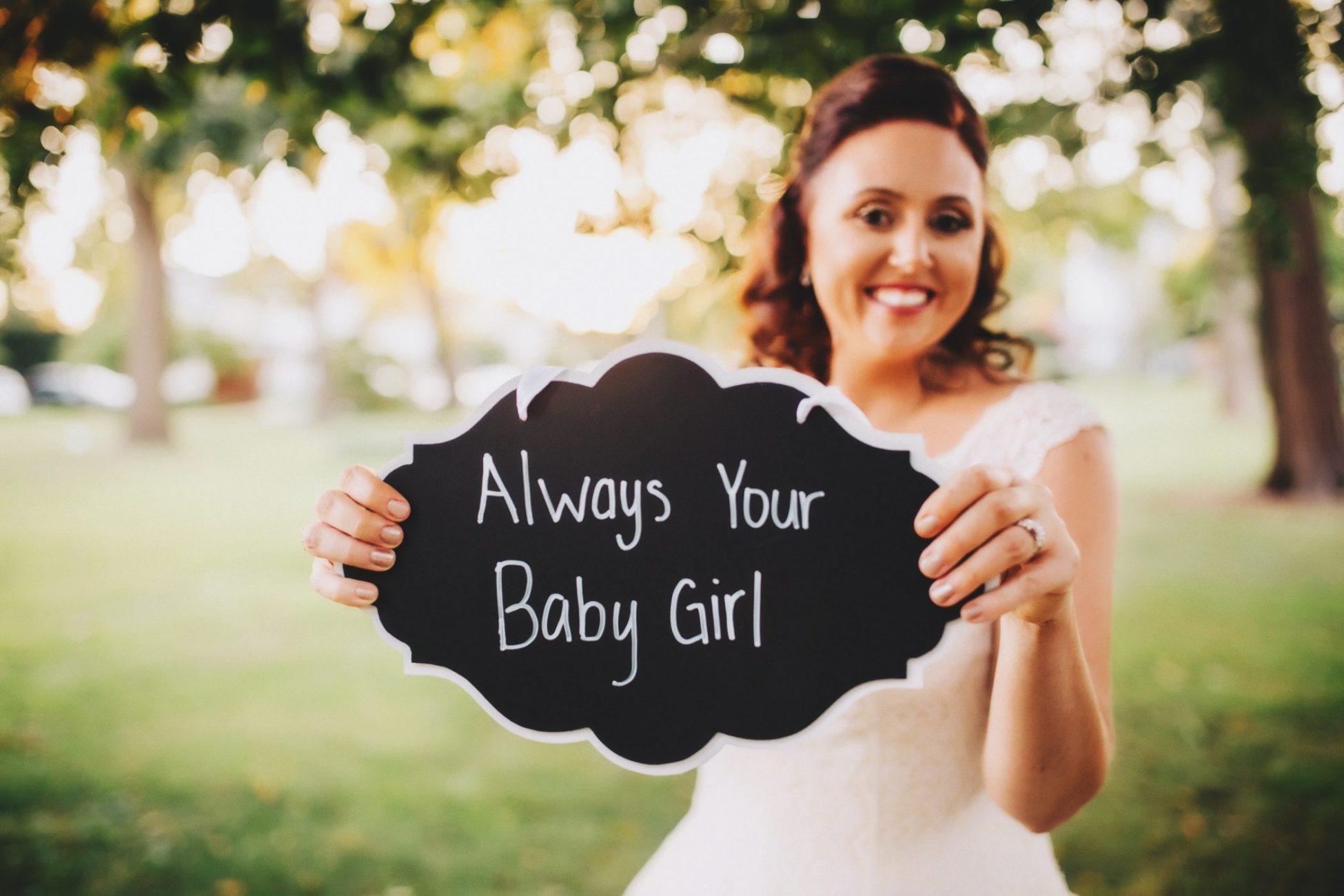 a woman holding up a sign that says, always your baby girl