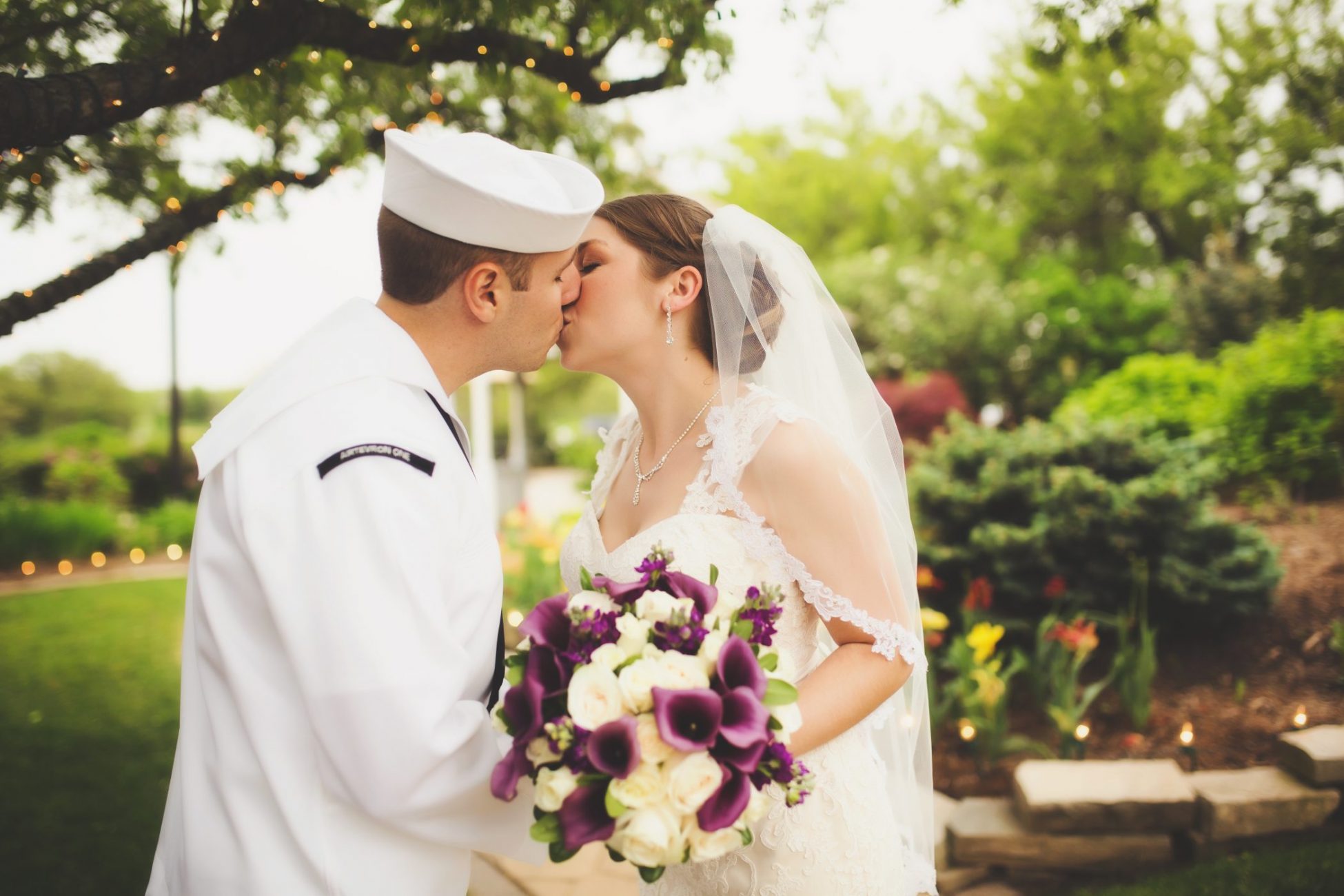 a bride and groom kissing under a tree