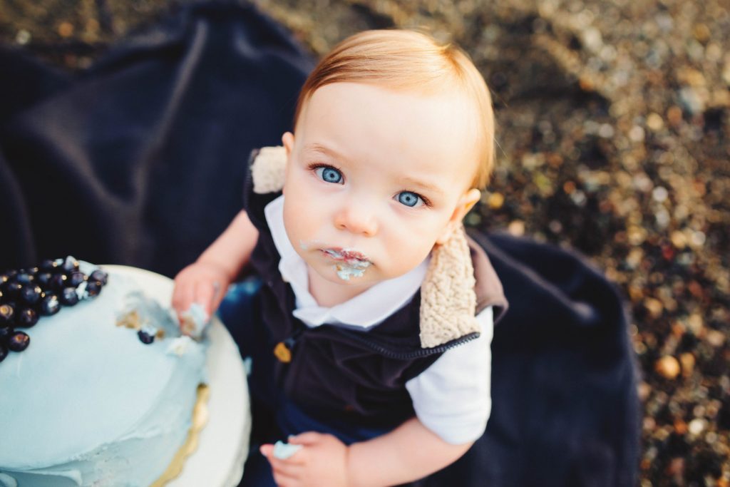 a baby is sitting next to a cake